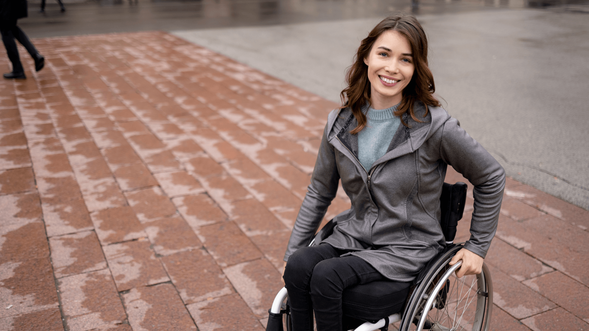 Smiling woman in wheelchair, in urban outdoor space.